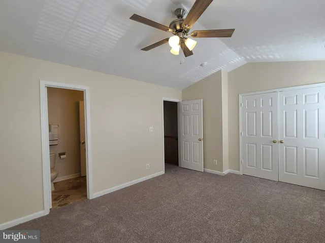 an empty room with chandelier fan and windows