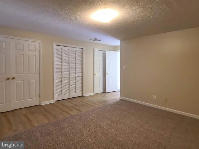 a view of an empty room with wooden floor fireplace and a window