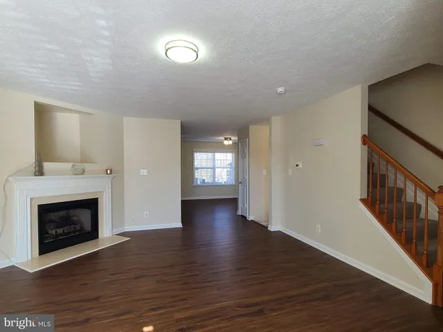 an empty room with wooden floor fireplace and windows