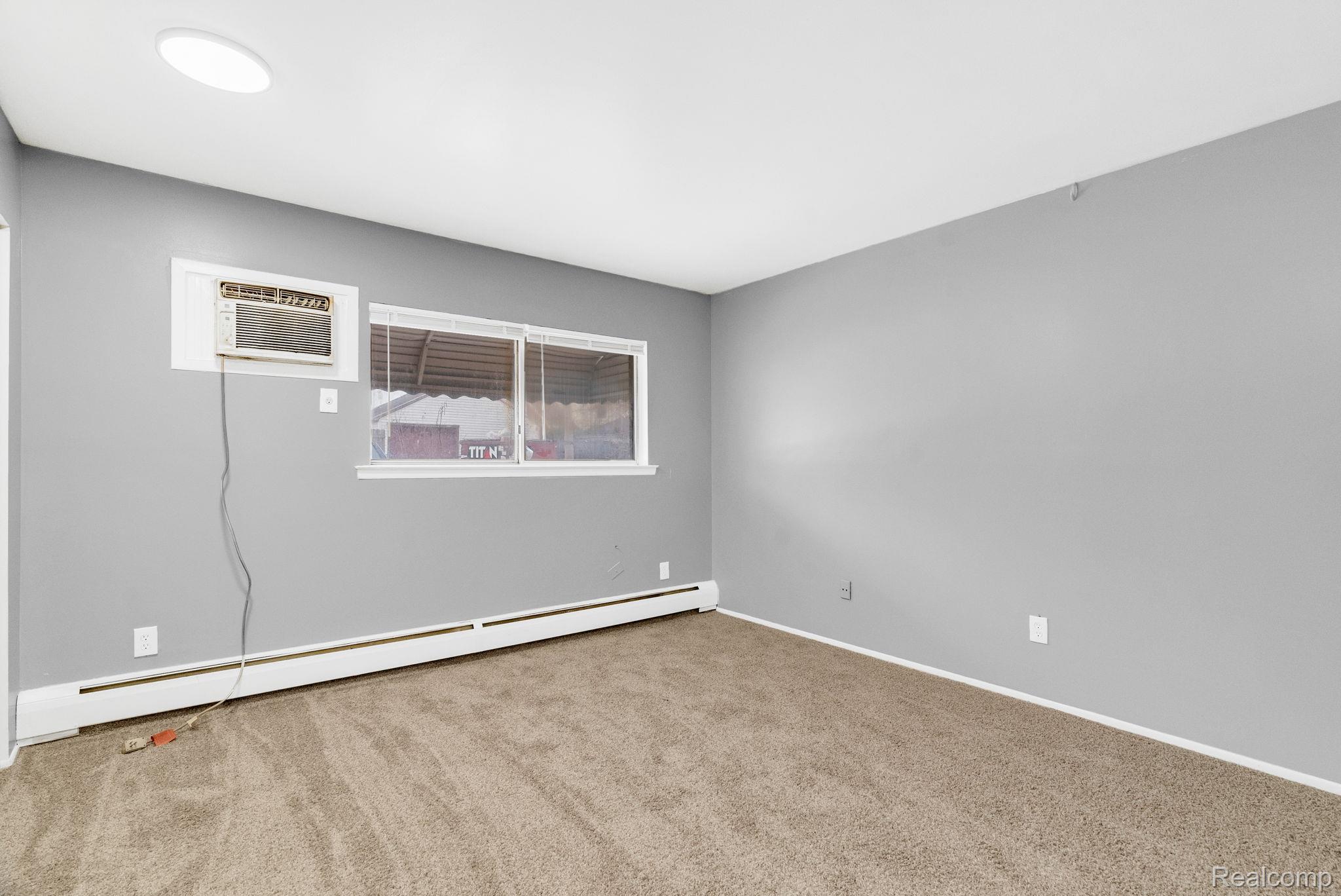 4535 Cadieux Road, Unit 42 / 210 Detroit, MI 48224 - Photo 13 of 16 Carpeted spare room featuring a baseboard heating unit and a wall mounted air conditioner