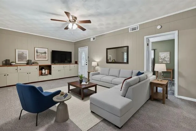 a living room with furniture a ceiling fan and a flat screen tv