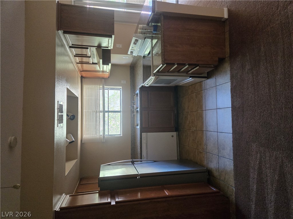 7200 West Pirates Cove Road, Unit 2047 Las Vegas, NV 89145 - Photo 3 of 17 A well-equipped kitchen features wooden cabinetry and tiled flooring, perfect for daily meal preparation.