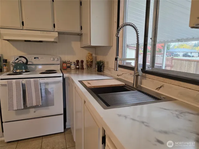 a kitchen with granite countertop white cabinets and white appliances