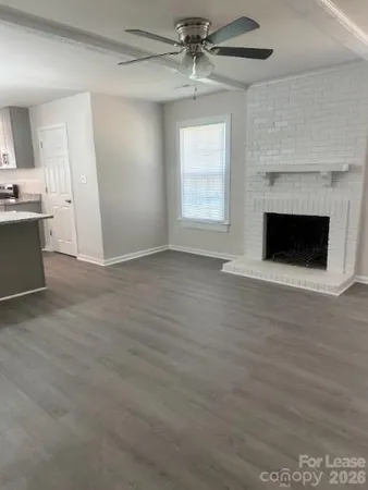 a view of a kitchen with a sink a kitchen island wooden floor and a fireplace
