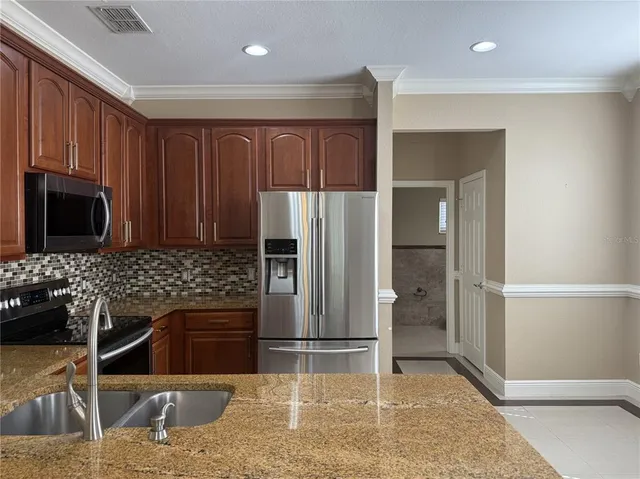 a kitchen with stainless steel appliances granite countertop a refrigerator and a stove top oven