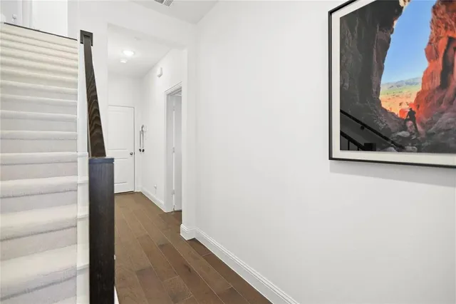 a view of a hallway with wooden floor and a bathroom