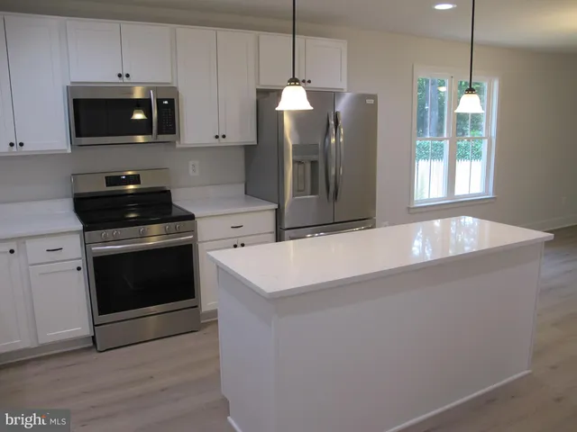 a kitchen with stainless steel appliances white cabinets white stove a microwave and a refrigerator