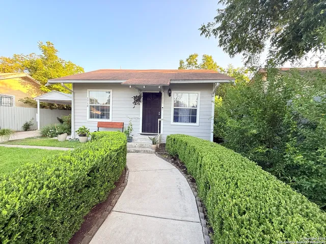 a view of a white house with large windows and a small yard
