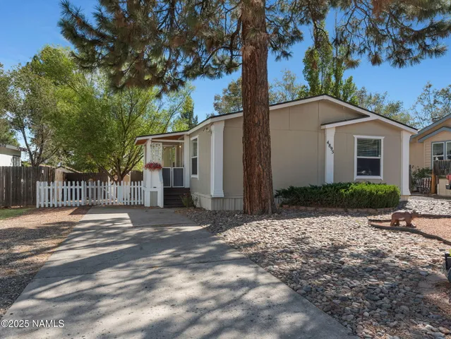 a front view of a house with a yard and tree