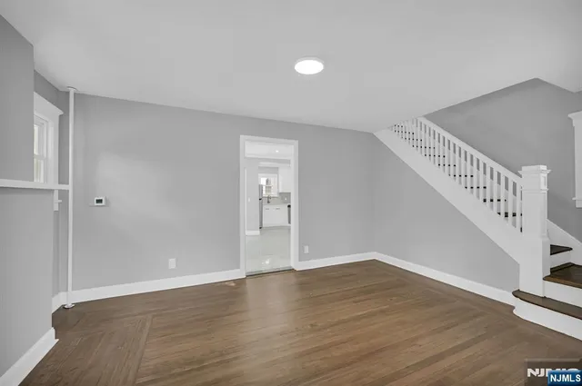 a view of an empty room with wooden floor and stairs