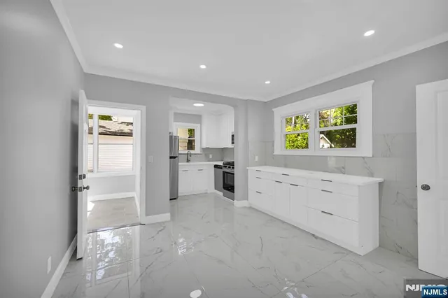 a kitchen with white cabinets and window