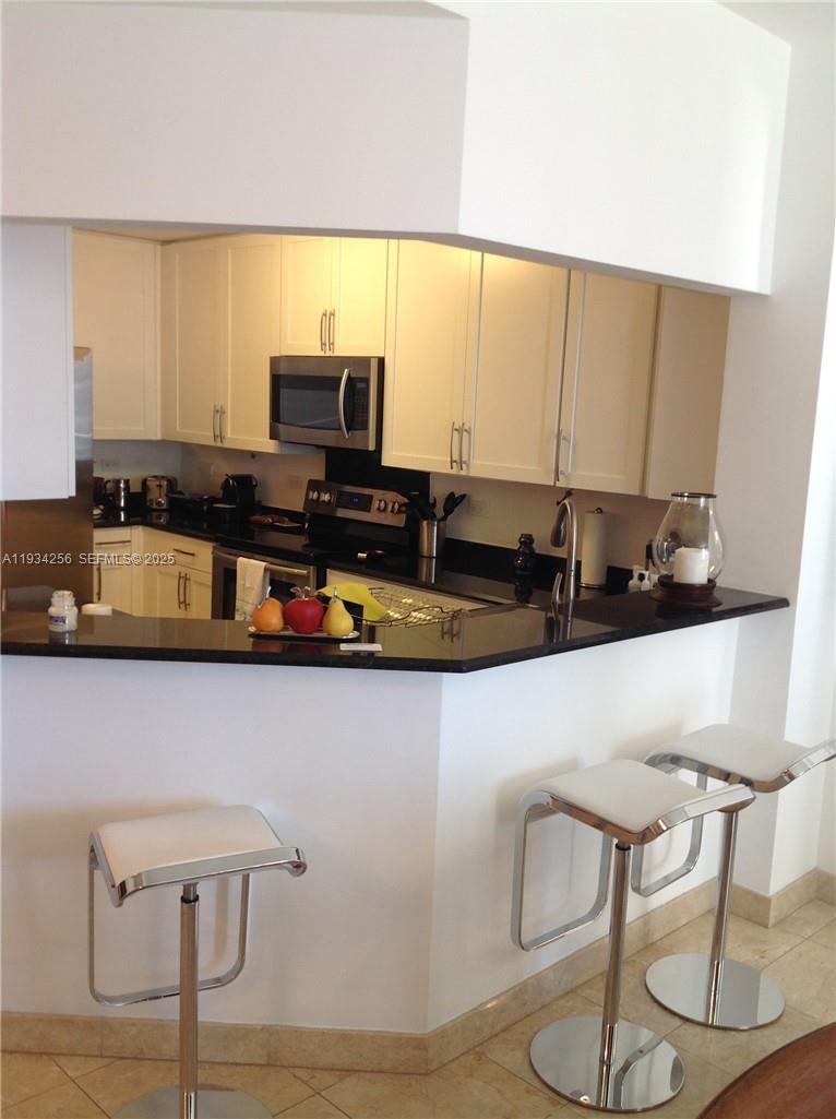 801 Brickell Key Boulevard, Unit 1004 Miami, FL 33131 - Photo 6 of 24 a kitchen with a table chair and microwave