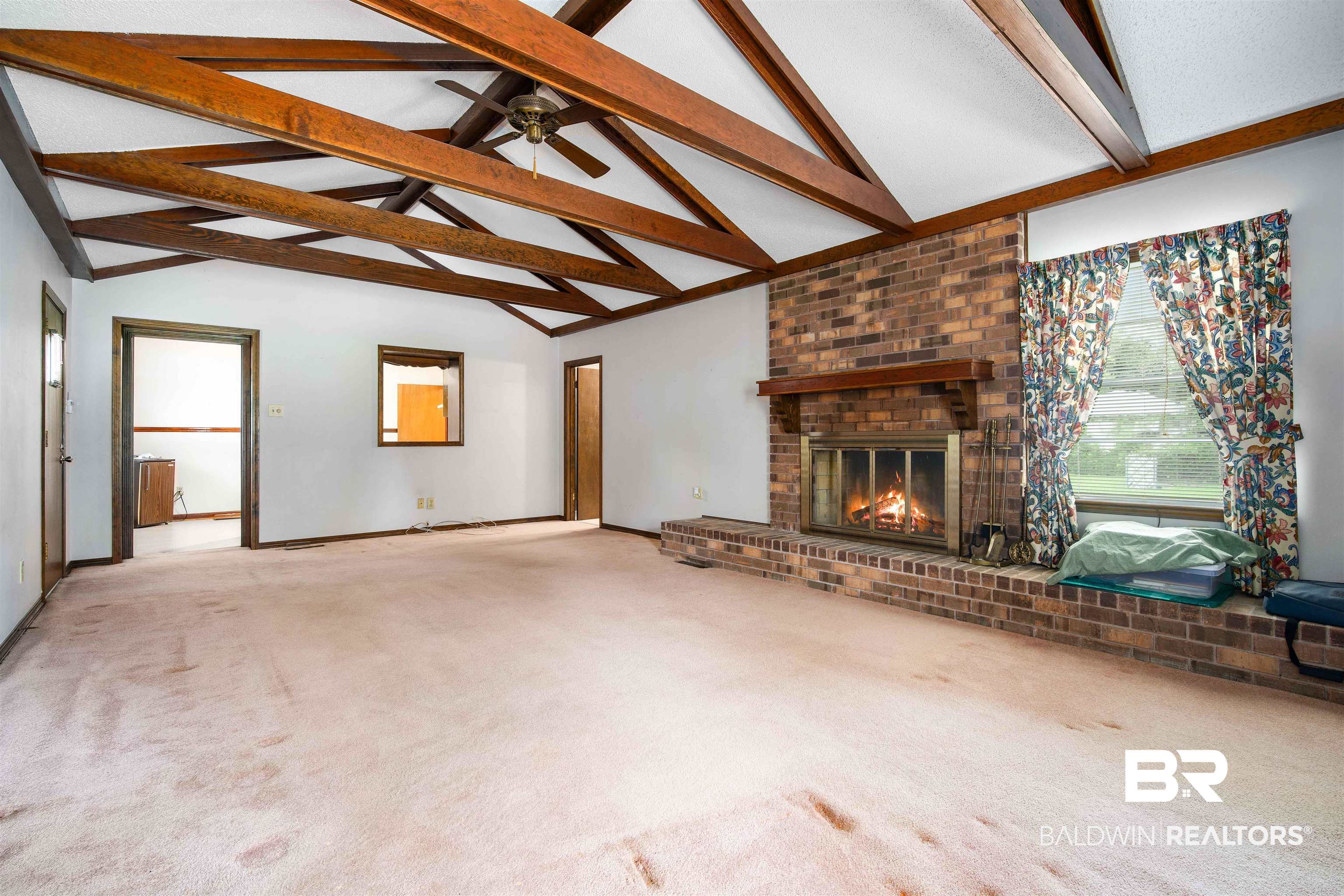 2300 Ellen Drive Mobile, AL 36605 - Photo 6 of 25 Unfurnished living room with ceiling fan, light colored carpet, lofted ceiling with beams, and a brick fireplace