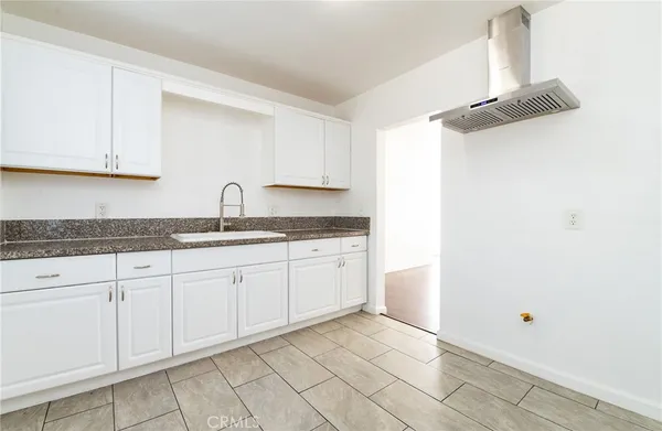 a kitchen with granite countertop white cabinets and a sink