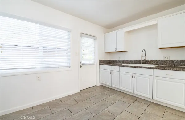 a kitchen with granite countertop white cabinets and a window