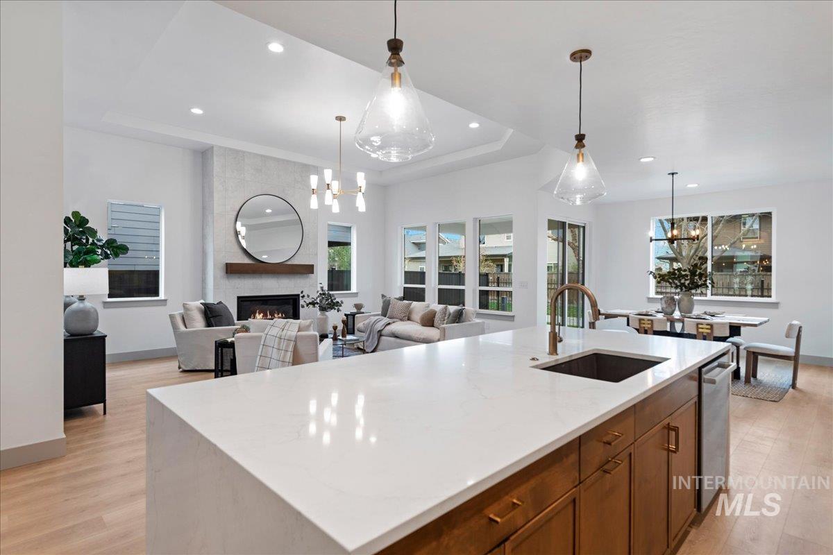 967 West Malbar Street Meridian, ID 83646 - Photo 13 of 33 Kitchen featuring suspended lighting, a kitchen island with sink, a fireplace, light stone counters, and wood finish cabinets