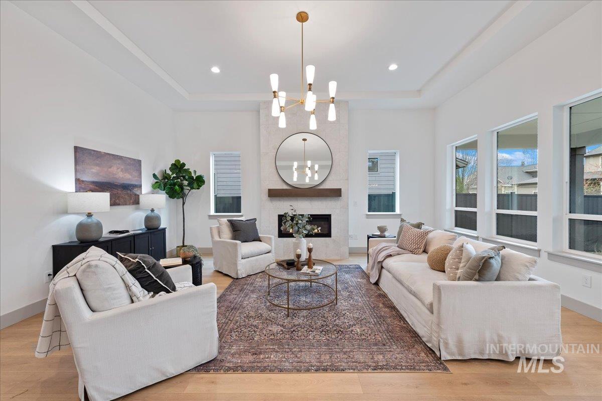 967 West Malbar Street Meridian, ID 83646 - Photo 5 of 33 Living area featuring a chandelier, a large fireplace, light wood-style flooring, and a tray ceiling