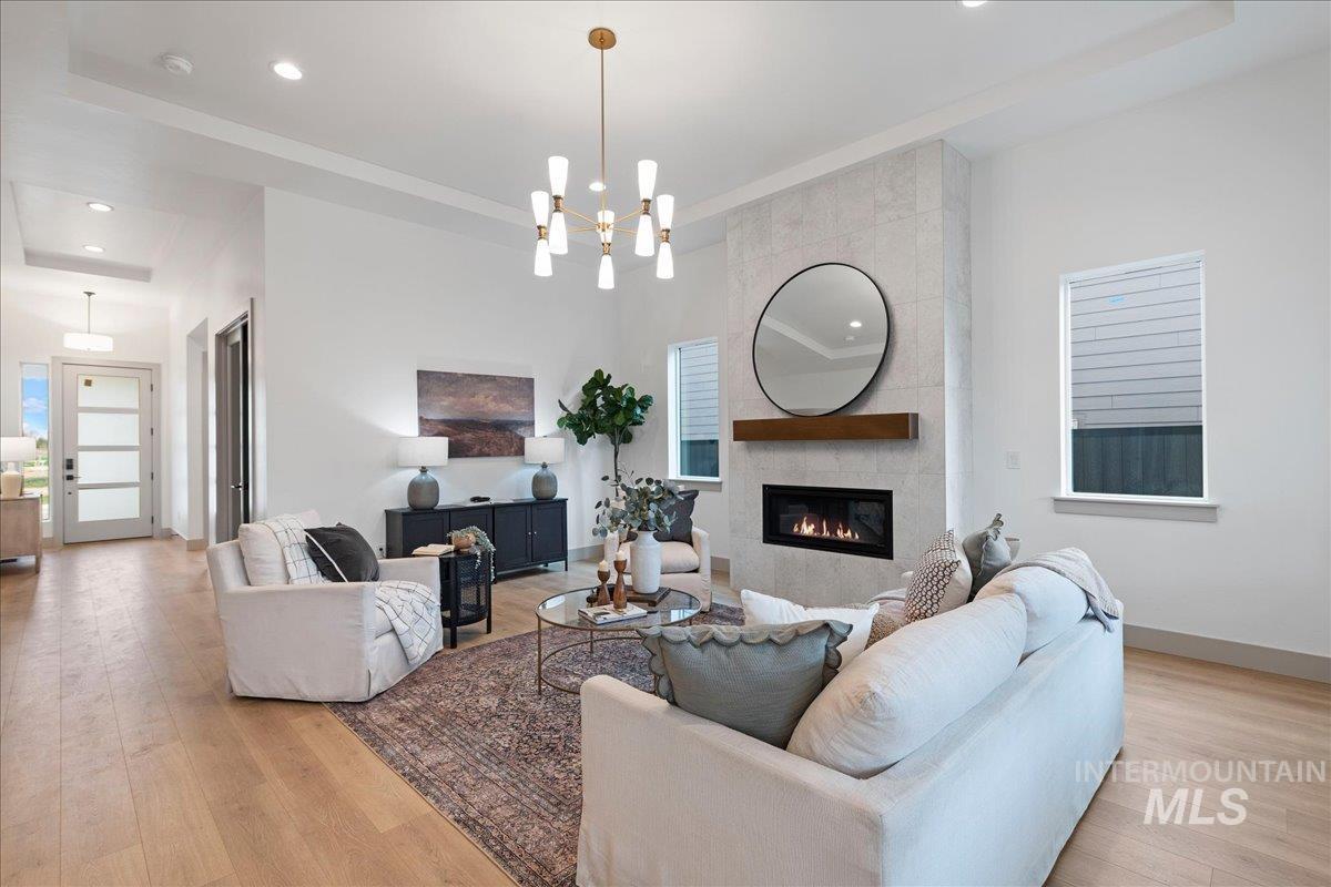 967 West Malbar Street Meridian, ID 83646 - Photo 6 of 33 Living room featuring light wood-type flooring, a raised ceiling, hanging lights, and a tile fireplace