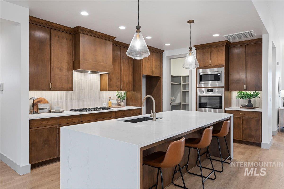 967 West Malbar Street Meridian, ID 83646 - Photo 8 of 33 Kitchen featuring light stone counters, tasteful backsplash, stainless steel appliances, and light wood-style flooring