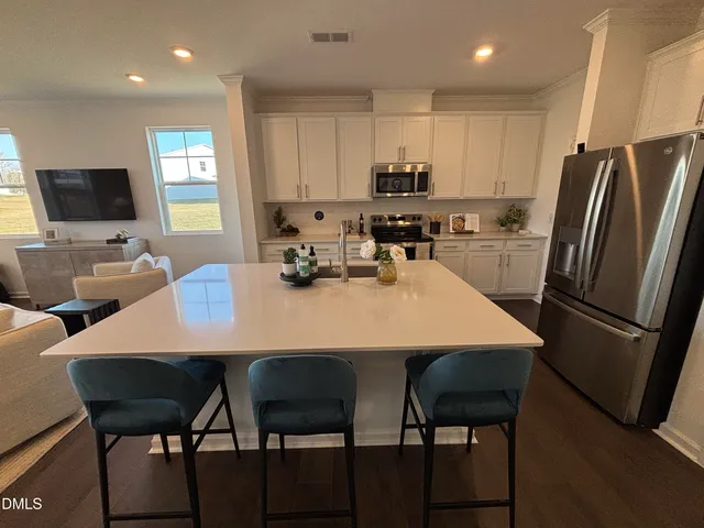 a kitchen with a dining table chairs and refrigerator