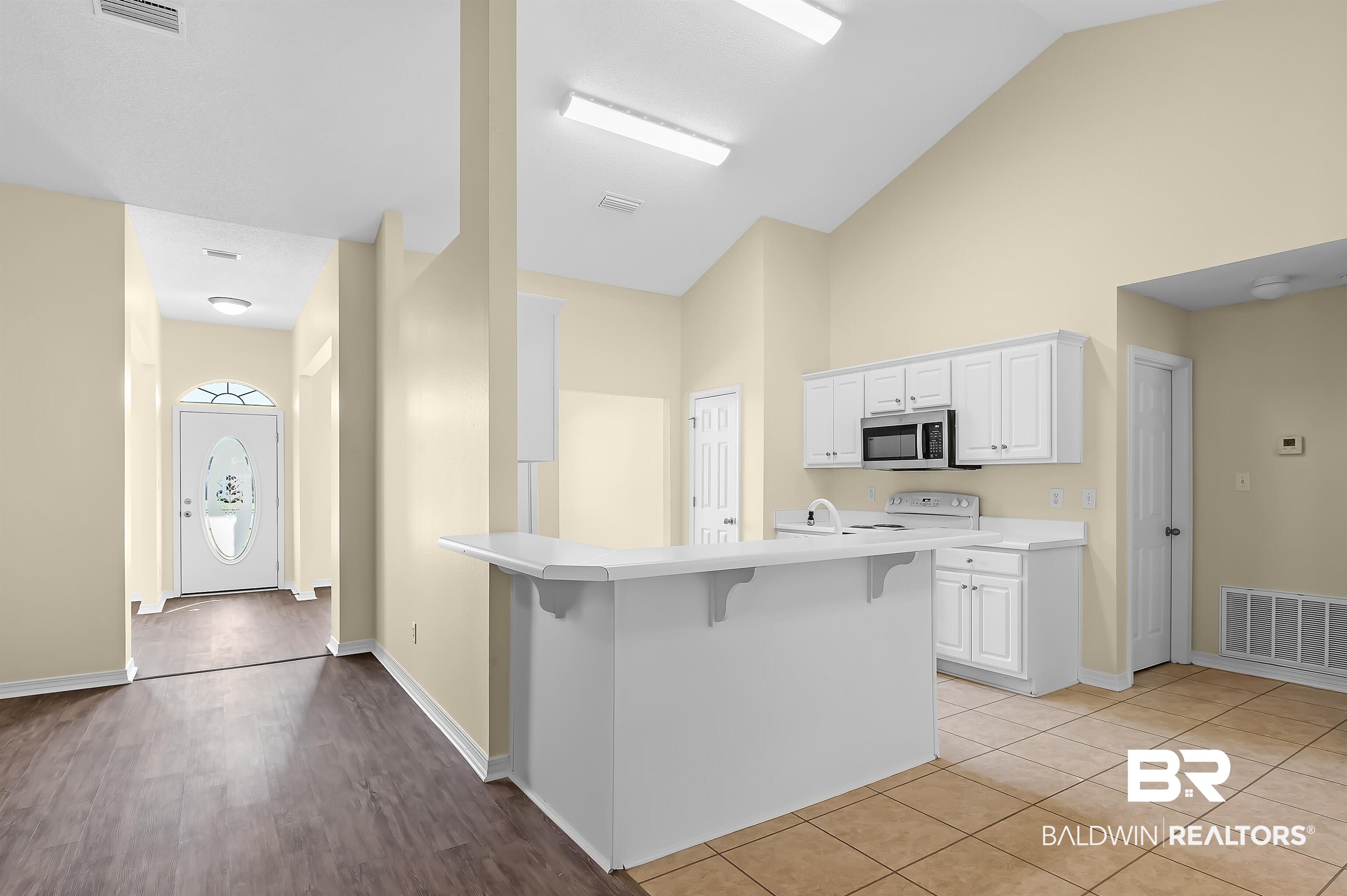 12443 Venice Boulevard Foley, AL 36535 - Photo 31 of 59 Kitchen featuring high vaulted ceiling, electric stove, white cabinetry, light hardwood / wood-style flooring, and a kitchen bar