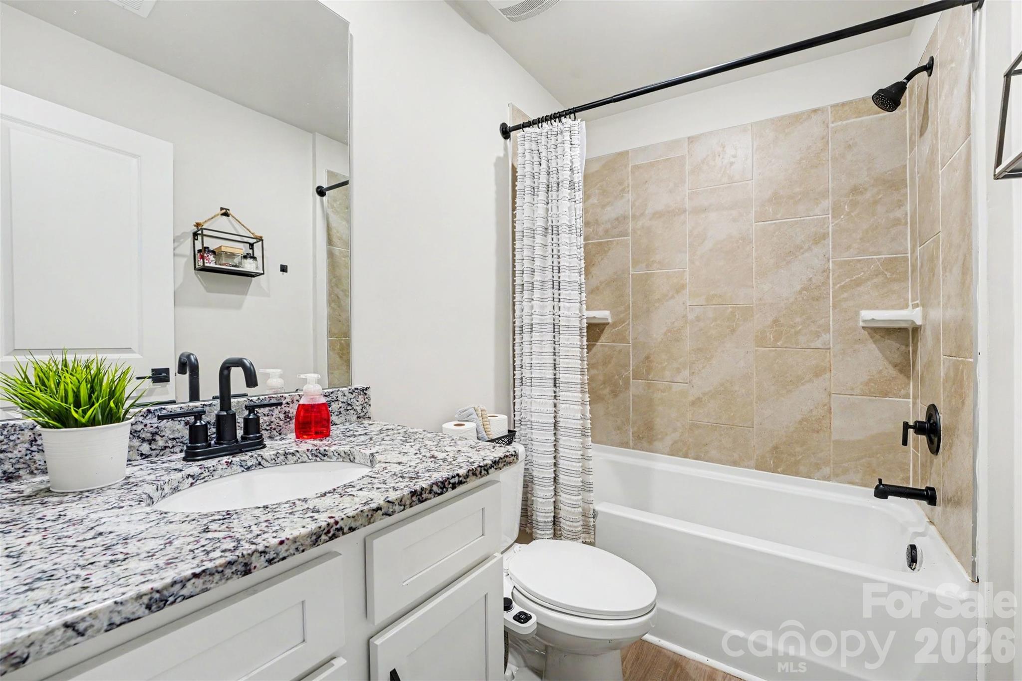 123 Brixham Loop Troutman, NC 28166 - Photo 15 of 18 a bathroom with a granite countertop sink a mirror a bathtub and shower