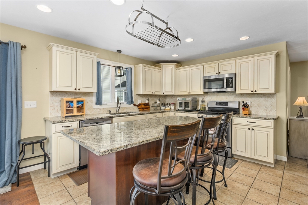 138 Sprague Street Fall River, MA 02724 - Photo 9 of 34 a kitchen with stainless steel appliances granite countertop a table chairs sink refrigerator and microwave