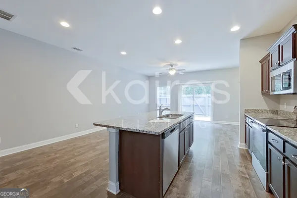 a kitchen with stainless steel appliances granite countertop a sink a stove and a wooden floors