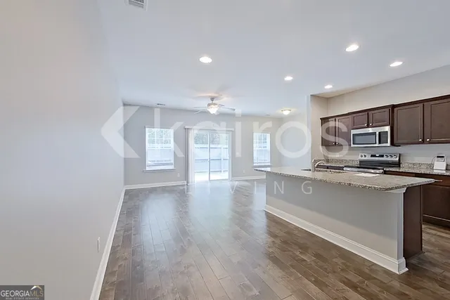 a open kitchen with stainless steel appliances granite countertop a stove a sink dishwasher and a microwave oven with large wooden cabinets