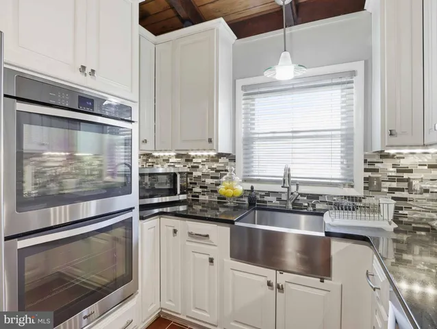 a kitchen with granite countertop a sink stainless steel appliances and cabinets