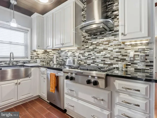 a kitchen with granite countertop a sink stainless steel appliances and cabinets