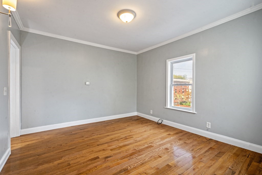 79 Derby Street, Unit 2 Somerville, MA 02145 - Photo 4 of 18 an empty room with wooden floor and windows