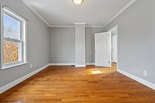 a view of an empty room with window and wooden floor