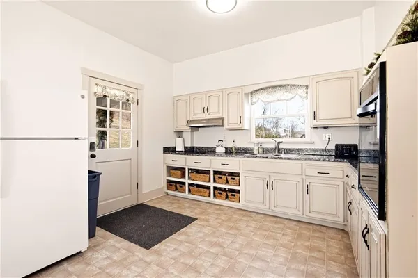 a kitchen with granite countertop a refrigerator stove top oven and sink