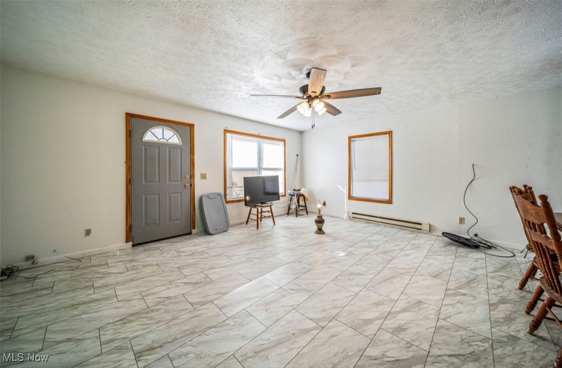 5919 North Bend Road Ashtabula, OH 44004 - Photo 18 of 24 Foyer entrance featuring a textured ceiling, a baseboard heating unit, light marble finish floors, and a ceiling fan