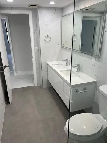 a bathroom with a granite countertop sink a toilet and a mirror