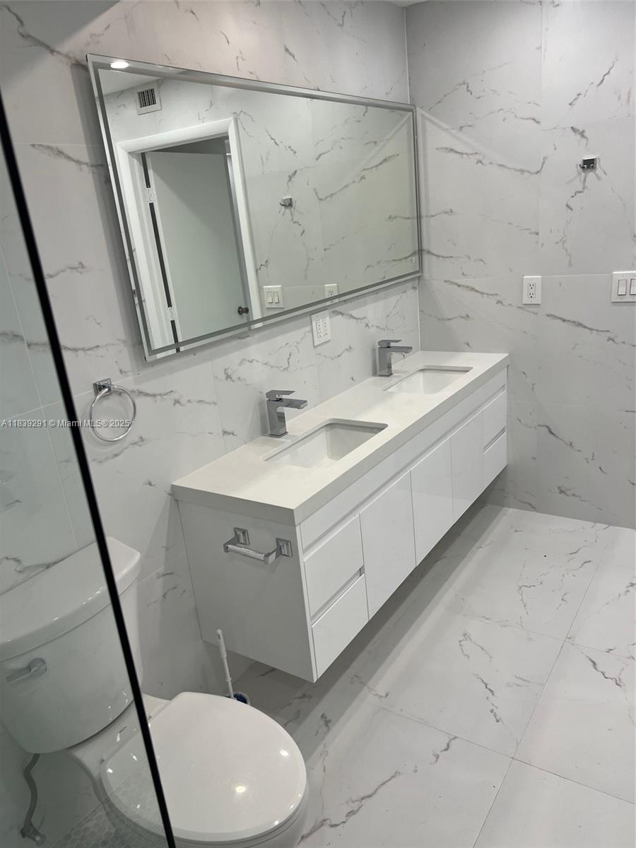 9801 Collins Avenue, Unit 15X/COMPLETE Bal Harbour, FL 33154 - Photo 15 of 24 a bathroom with a sink mirror vanity and toilet