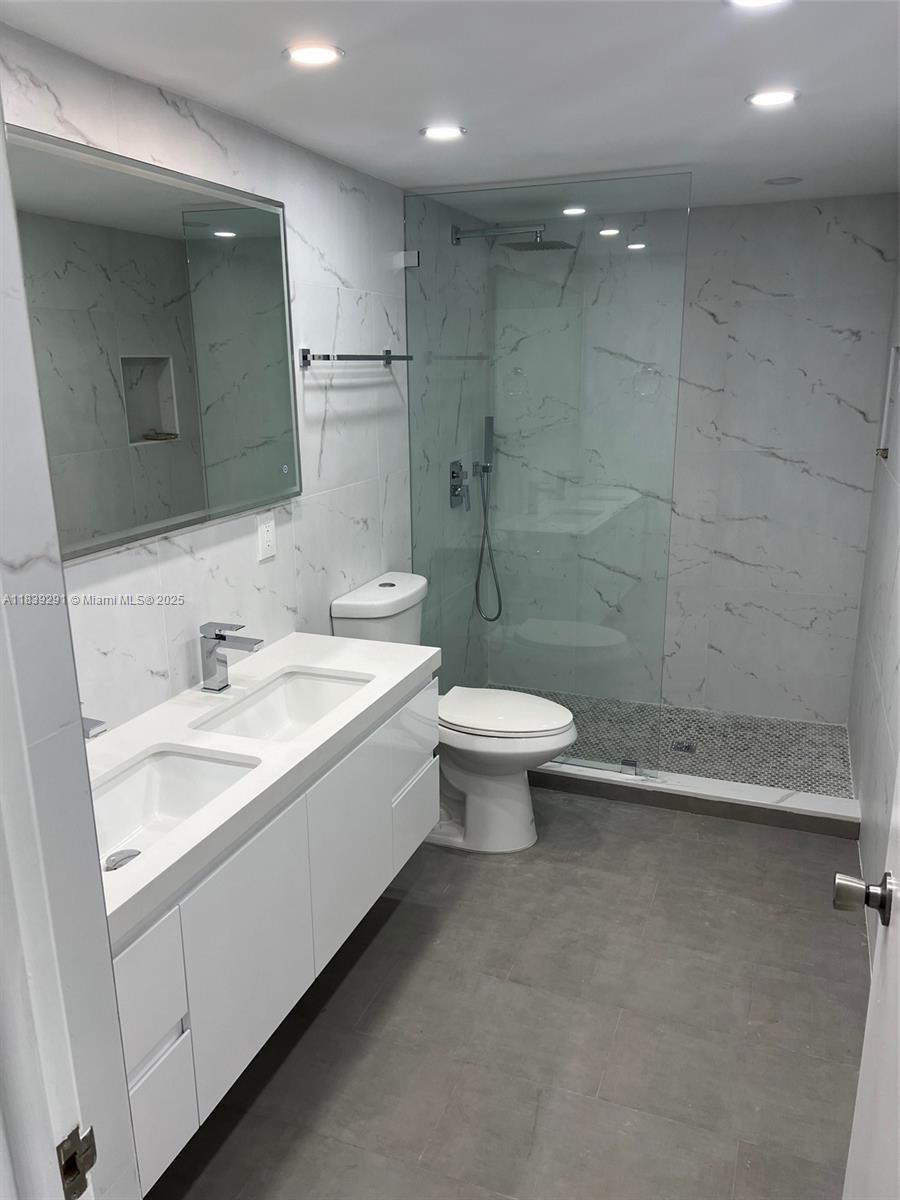 9801 Collins Avenue, Unit 15X/COMPLETE Bal Harbour, FL 33154 - Photo 16 of 24 a bathroom with a granite countertop sink a toilet and a mirror