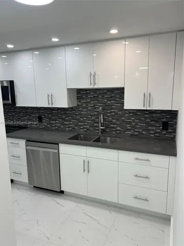 a kitchen with stainless steel appliances a refrigerator a stove a sink and white cabinets