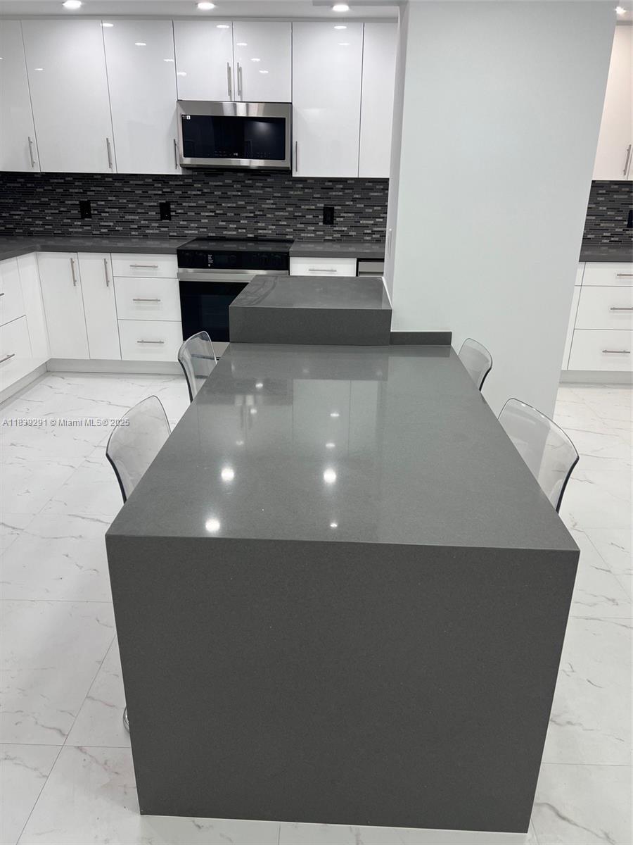 9801 Collins Avenue, Unit 15X/COMPLETE Bal Harbour, FL 33154 - Photo 5 of 24 a kitchen with stainless steel appliances a refrigerator a stove a sink and white cabinets