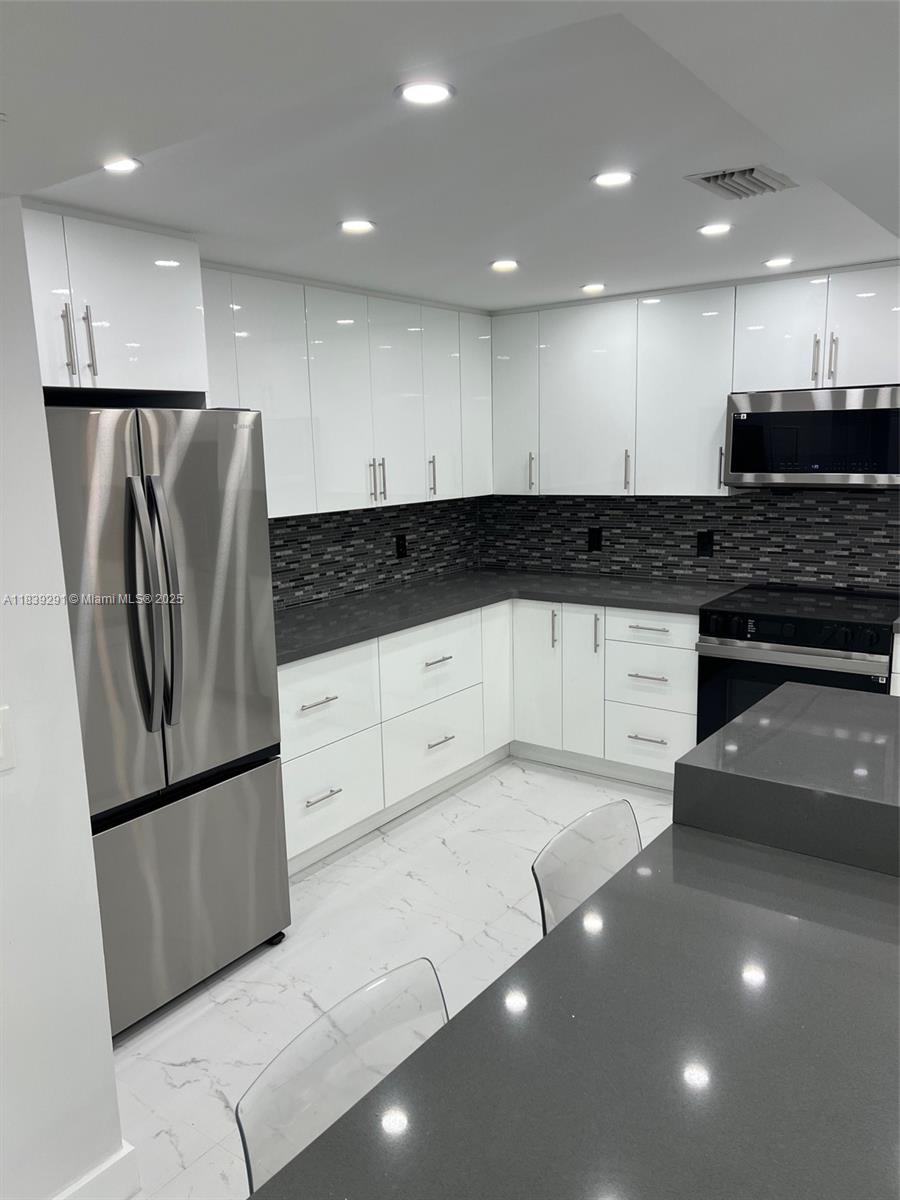 9801 Collins Avenue, Unit 15X/COMPLETE Bal Harbour, FL 33154 - Photo 6 of 24 a kitchen with stainless steel appliances granite countertop a refrigerator and a stove top oven