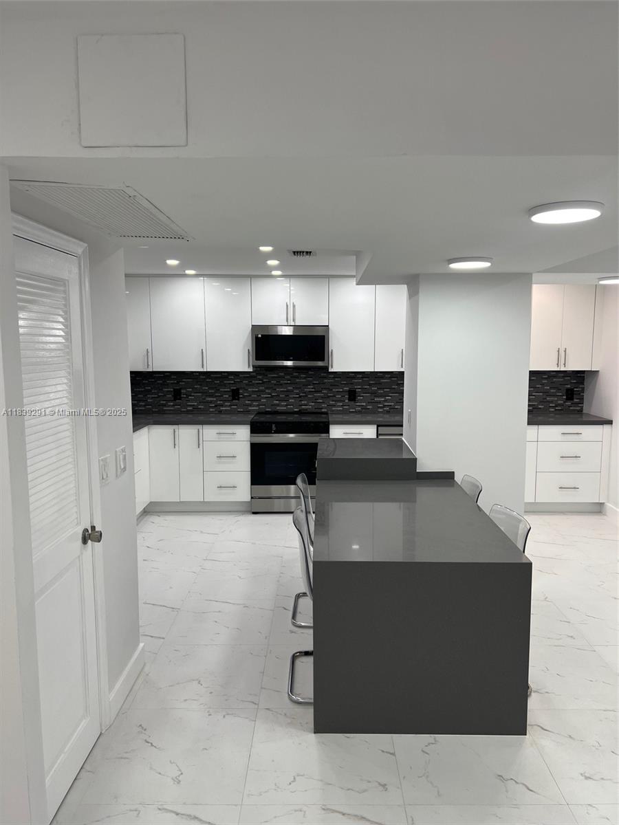 9801 Collins Avenue, Unit 15X/COMPLETE Bal Harbour, FL 33154 - Photo 8 of 24 a kitchen with stainless steel appliances a stove a sink a microwave a refrigerator and cabinets