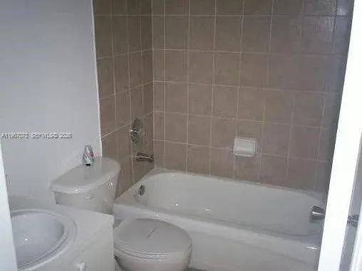a bath tub sitting next to a white toilet and sink
