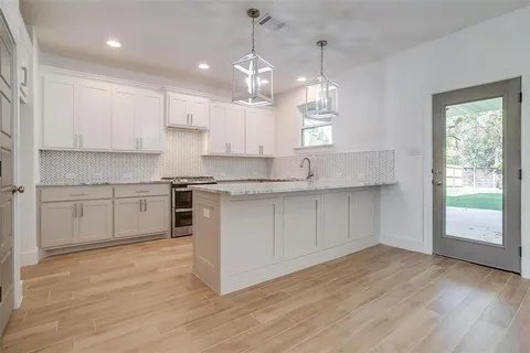 a kitchen with kitchen island granite countertop a sink cabinets and wooden floor