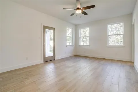 a view of an empty room with a window and wooden floor
