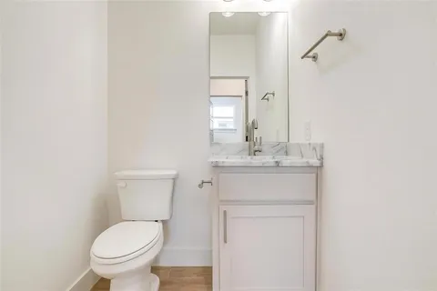 a bathroom with a toilet sink vanity and mirror
