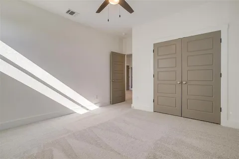 an empty room with closet and a ceiling fan