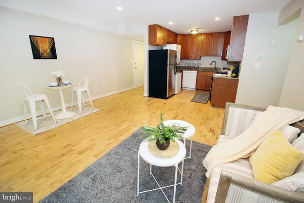 a kitchen with stainless steel appliances kitchen island granite countertop a dining table chairs and a refrigerator