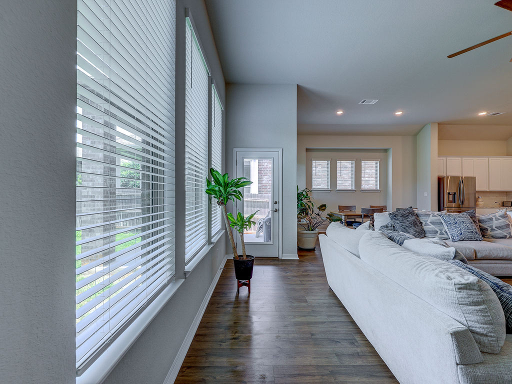 229 Heartleaf Road San Marcos, TX 78666 - Photo 22 of 40 Rich hardwood flooring extends through this airy living area, featuring multiple windows and a glass-paneled door.