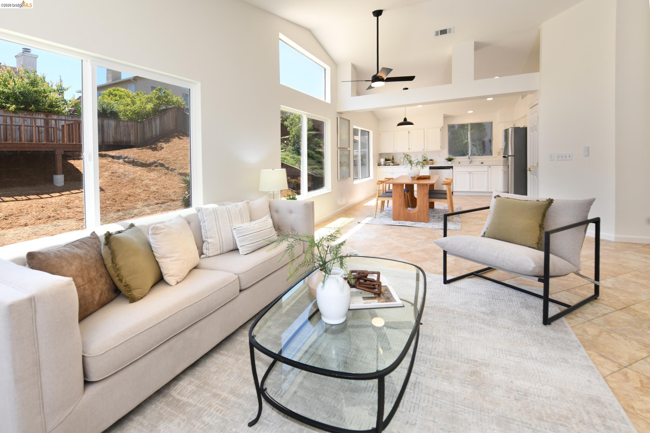 512 Burdick Drive Bay Point, CA 94565 - Photo 12 of 50 Open-concept living space featuring high vaulted ceilings, expansive windows, a ceiling fan, and tile flooring extending into the kitchen and dining areas